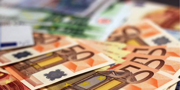 Meerdere vijftig eurobiljetten verspreid over een tafel met andere eurobiljetten op de achtergrond