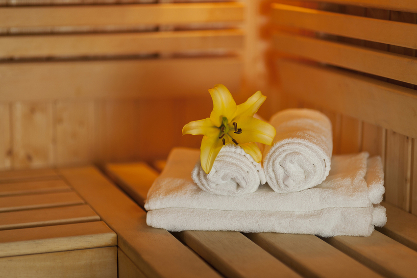Opgerolde handdoeken met bloem in een sauna als voorbeeld van een bewuste wellness-ervaring
