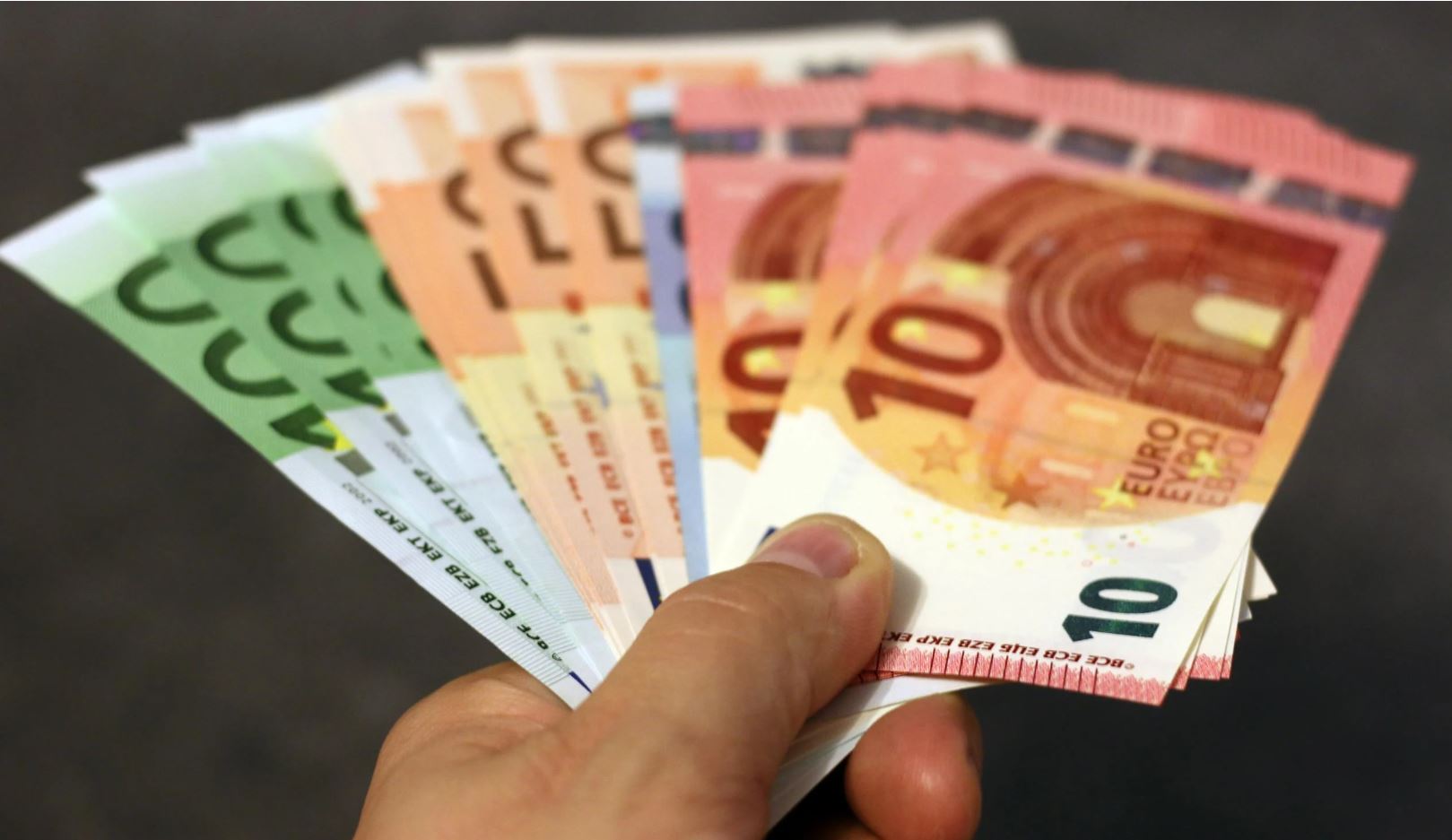 Hand met waaier van eurobiljetten van 10 tot 100 euro in verschillende kleuren